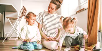mom and kids working on an art project on the floor