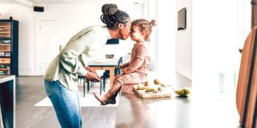 mother kissing her daughter on the forehead in a kitchen