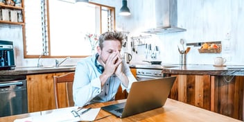 man looking at his computer in anguish trying to manage his finances