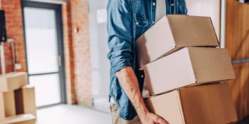 man carrying a stack of cardboard moving boxes