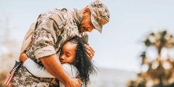 member of the armed forces embracing his daughter while on leave