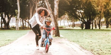 mother teaching young son to ride a bike