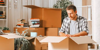 man packing moving boxes in a house