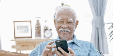 retired man smiling and looking at his phone