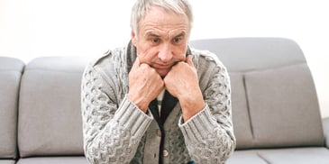 older man suffering from anxiety sitting alone on a couch