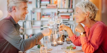 Couple at a romantic dinner cheers with wine glasses