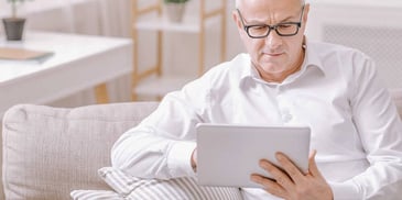 older man reading on his tablet