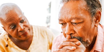 retired couple sitting apart and looking concerned