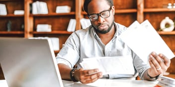 man looking at mail and other papers at a desk