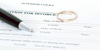 wedding ring and pen on top of divorce petition