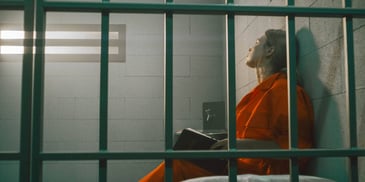 female prisoner with a journal in a jail cell