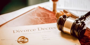divorce decree and gold rings sitting on a table by a judge's gavel