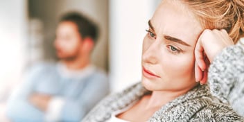 unhappy couple sitting far apart in a living room