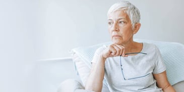 pensive older woman with white hair and glasses