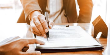 person pointing to where to sign a paper