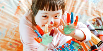 happy girl with downs syndrome finger painting