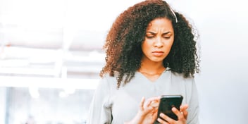 woman frowns at phone as she texts
