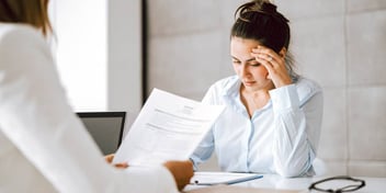 woman reading piece of paper with another woman