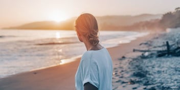 Woman looks over the beach at sunset