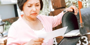 woman looking upset at the divorce papers she just received in the mail