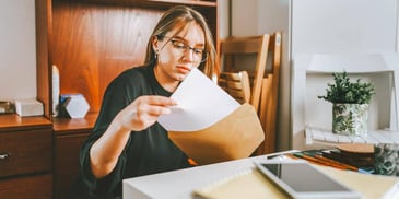 woman putting paperwork into a manila envelope