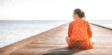 woman sitting quietly on a pier looking at the water