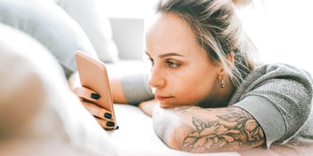 young woman with tattoos looking at her phone