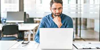 man sitting in a professional office doing work on a laptop