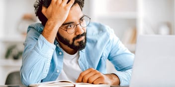 confused man looking at a laptop