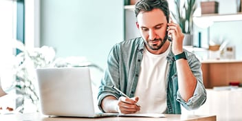 man working on his taxes while talking on the phone